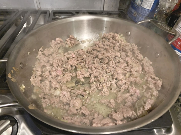 Ground pork cooking in a skillet.