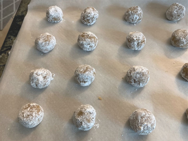 Honey cookie dough balls rolled in powdered sugar, ready to bake.