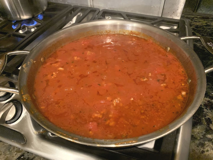 A pan full of simmering pasta sauce.