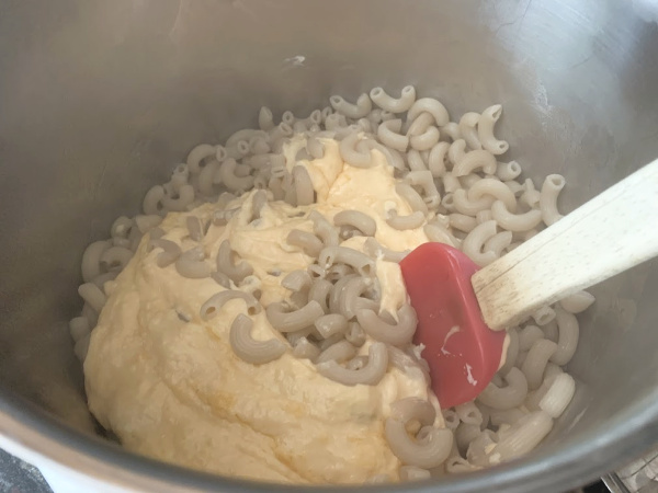 Mixing the cooked gluten free macaroni into the cheese.