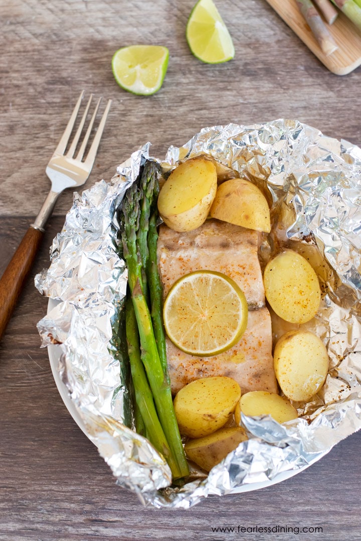 An open foil packet with mahi mahi, potatoes, and asparagus.