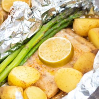 Cooked mahi mahi filet with asparagus and potatoes in a foil packet.