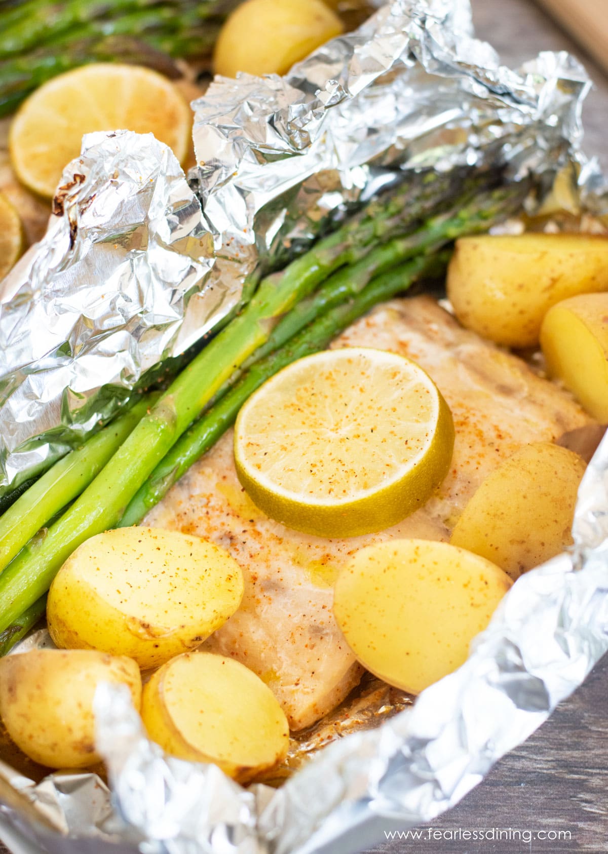 Cooked mahi mahi filet with asparagus and potatoes in a foil packet.