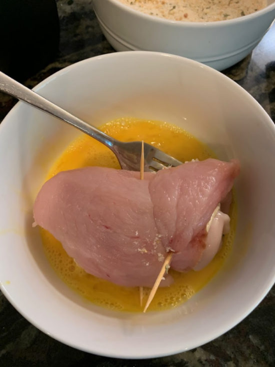 Dipping the chicken breast in the egg wash.