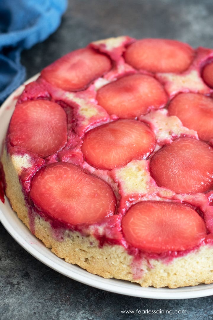 A whole gluten free plum upside down cake on a big plate.