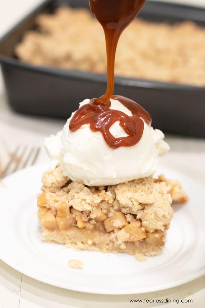 Drizzling caramel over an apple pie bar and ice cream.
