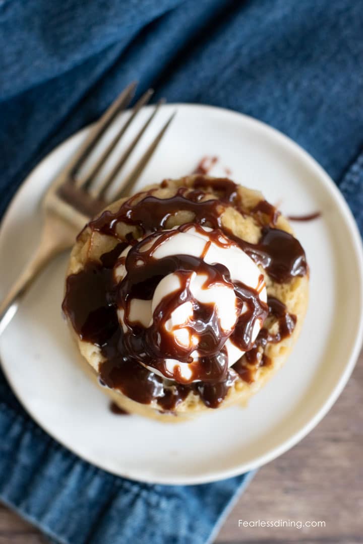 Top view of a banana mug cake topped with frosting and fudge sauce.