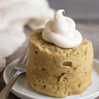 A frosted gluten free banana mug cake on a plate.