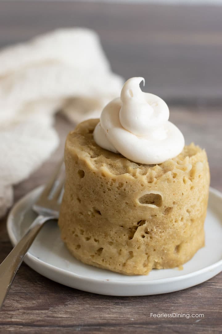 A frosted gluten free banana mug cake on a plate.