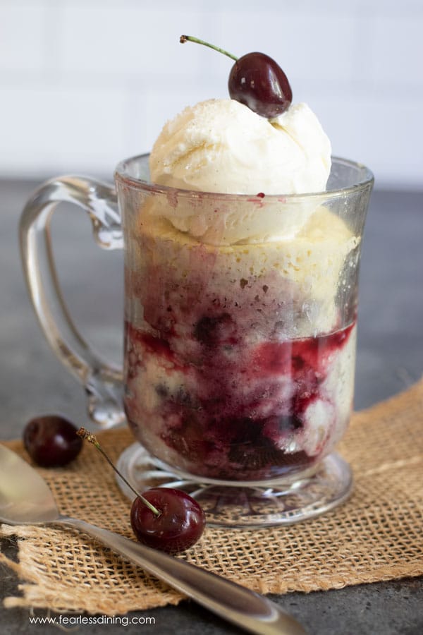 A gluten-free cherry cobbler mug cake in a glass mug.