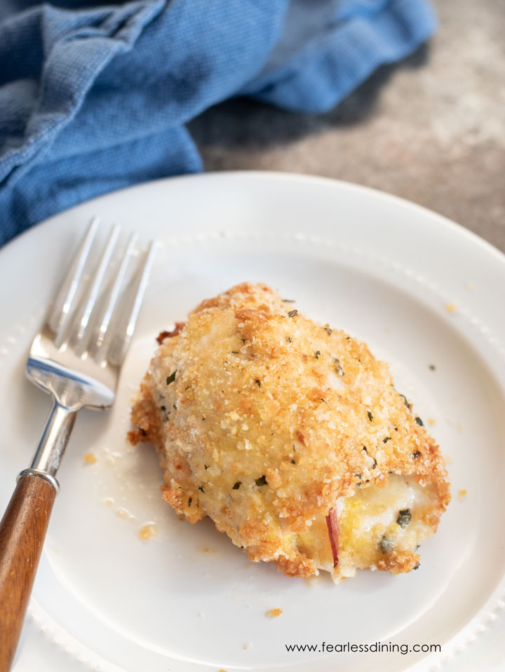 The top view of a piece of chicken cordon bleu on a plate with a fork.