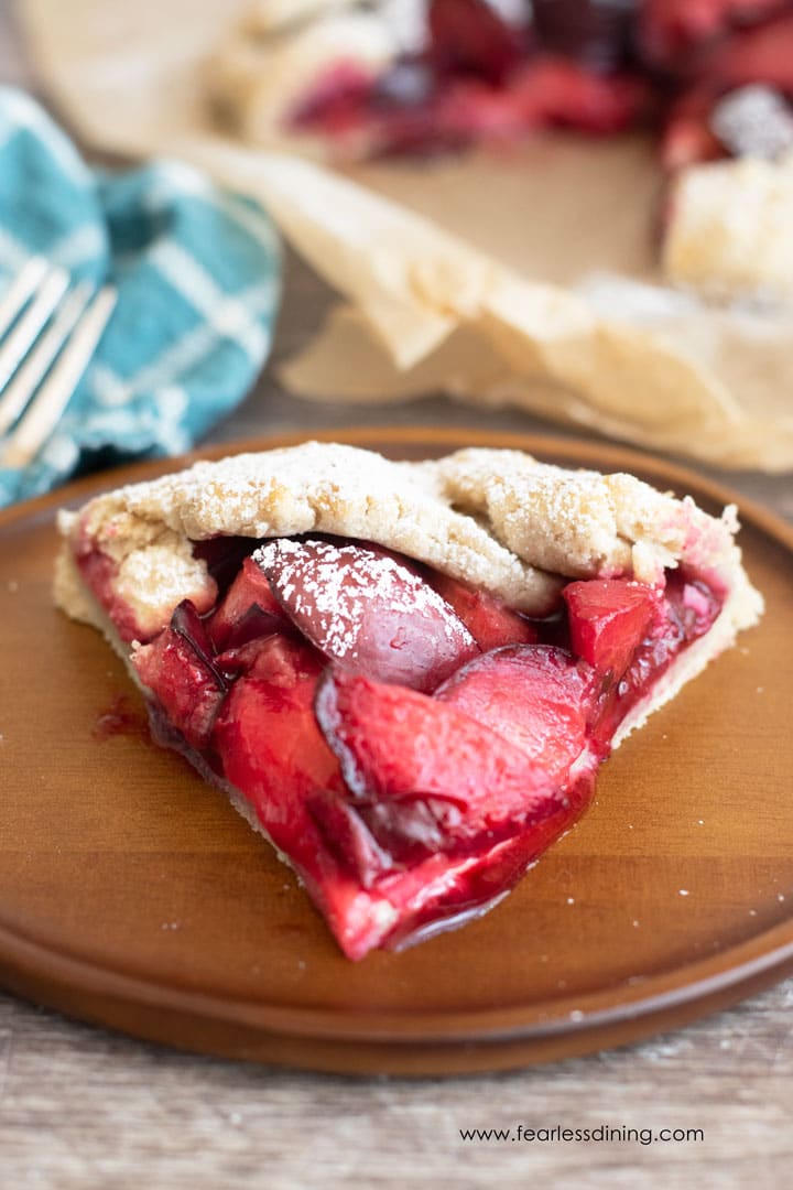 The front on view of a slice of plum galette on a wooden plate.