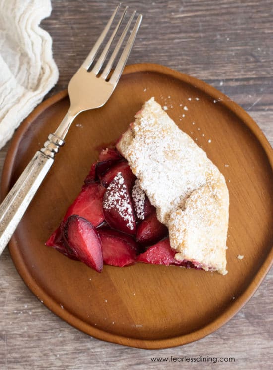 The top view of a slice of plum galette on a wooden plate.