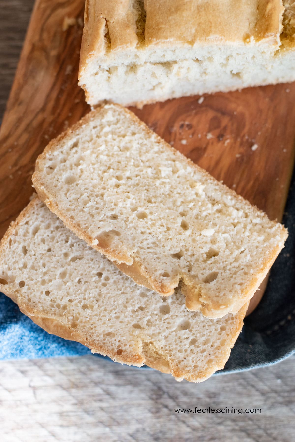 The top view of a sliced loaf of gluten free sourdough sandwich bread on a wooden cutting board.