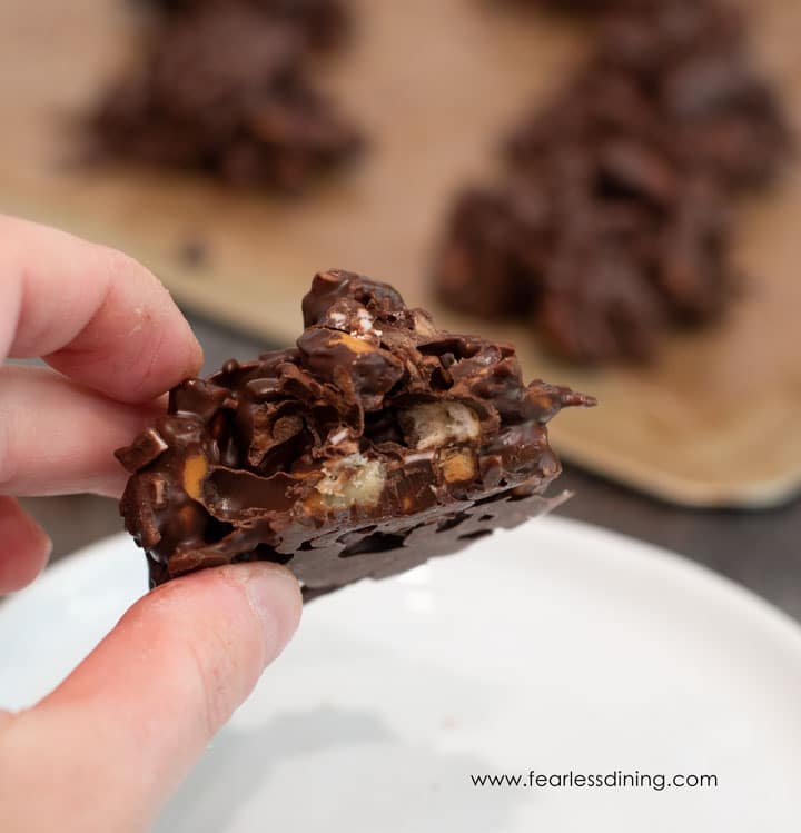 Fingers holding a haystack cookie with a bite taken out so you can see inside.