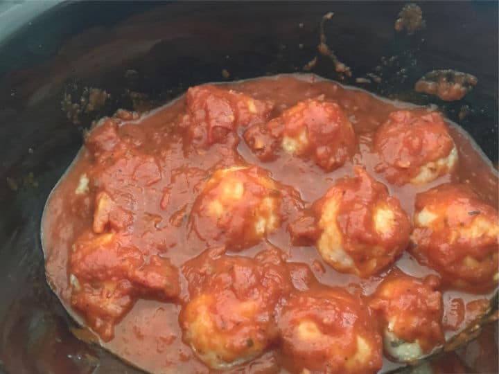 Meatballs cooking in a slow cooker.