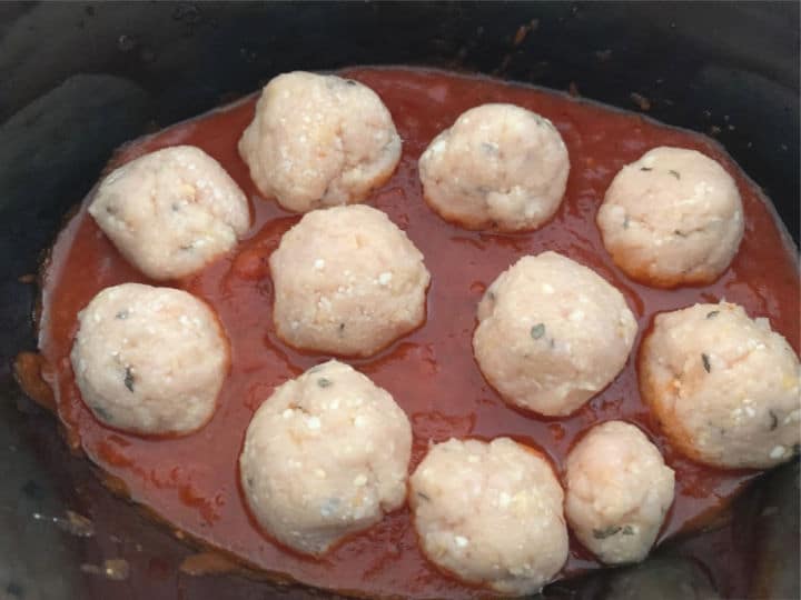 Raw meatballs in pasta sauce ready to cook.