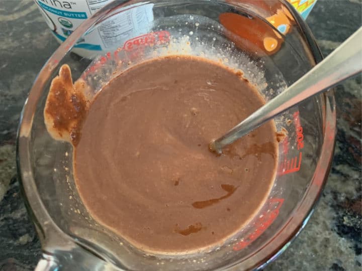 The melted coconut oil and chocolate wet ingredients in a glass measuring cup.