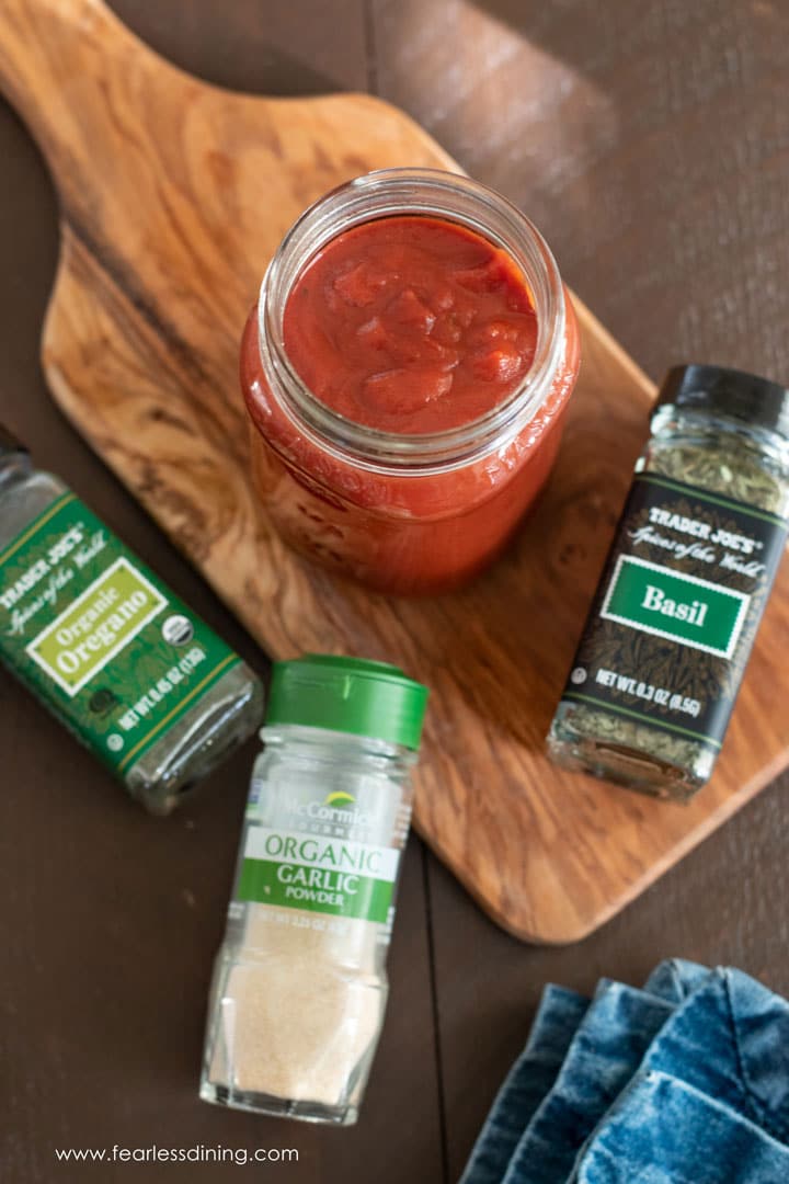 Top view of a jar of pizza sauce with a bottle of basil, oregano, and garlic powder next to the jar.