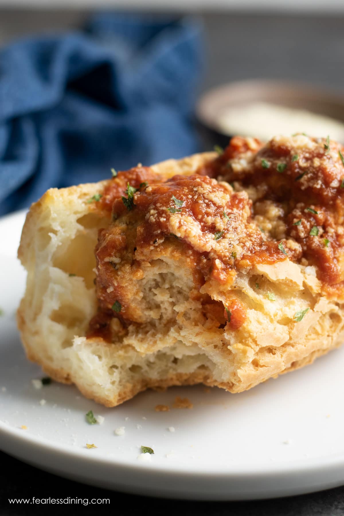 A ground pork meatball grinder with a bite taken out so you can see inside the meatball.