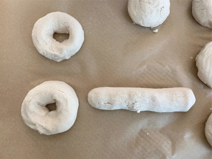 Rolling out bagel dough and shaping the bagels into large circles.