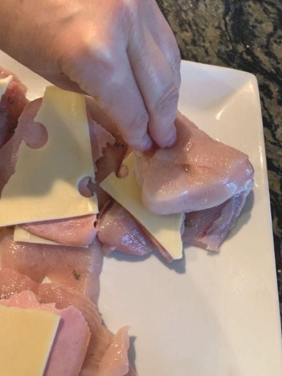 Adding the ham layer and starting to roll the chicken breast.