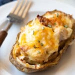 a loaded twice baked potato on a plate with a fork