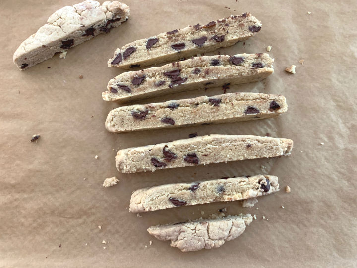 Partially baked biscotti sliced and getting turned on its side.
