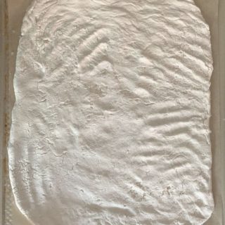an oval shaped gluten free sourdough pizza crust on a baking sheet