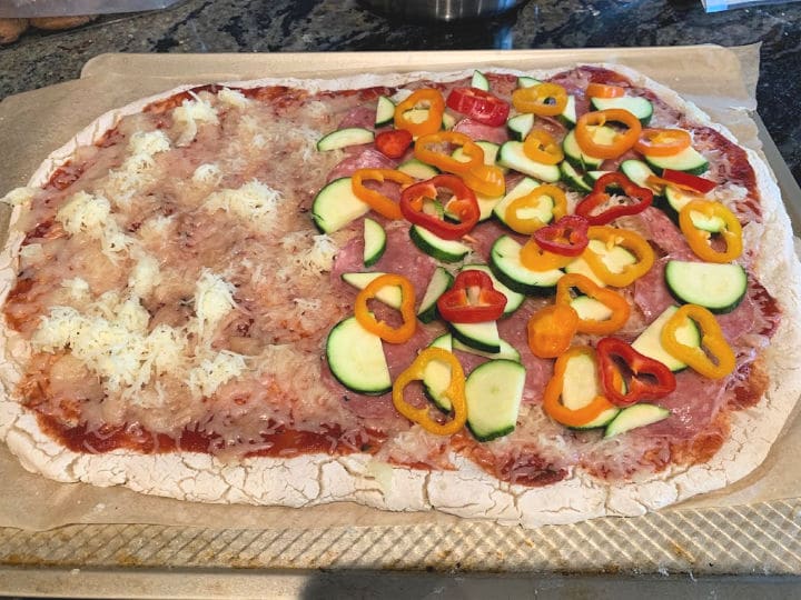 A pizza crust with sauce cheese and vegetables on top.