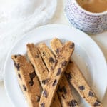 slices of gluten free chocolate chip biscotti on a plate next to a cup of coffee