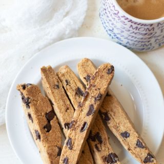 slices of gluten free chocolate chip biscotti on a plate next to a cup of coffee