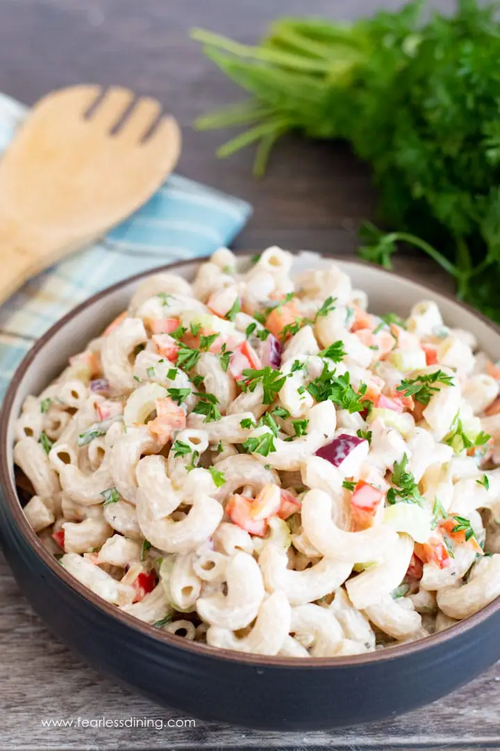 a big bowl of deli style macaroni salad with a serving spoon and parsley