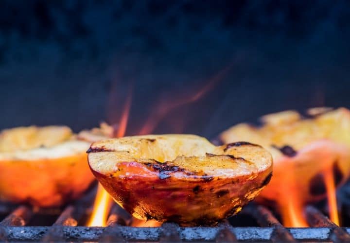 Peach halves griling on a grill.