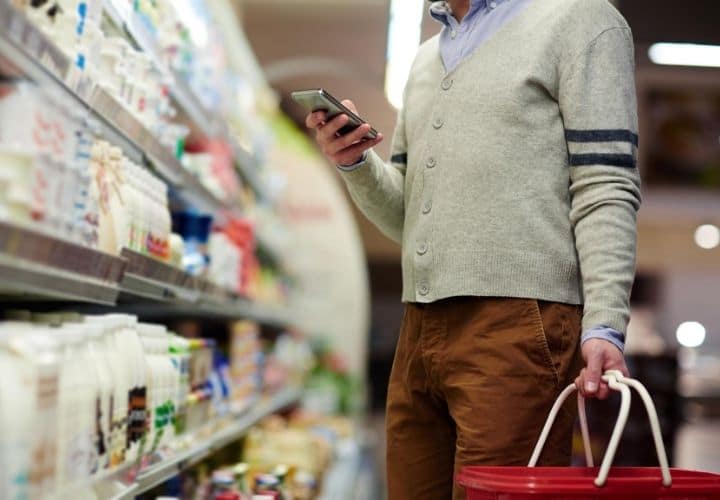 A grocery shopper using phone to check ingredients.