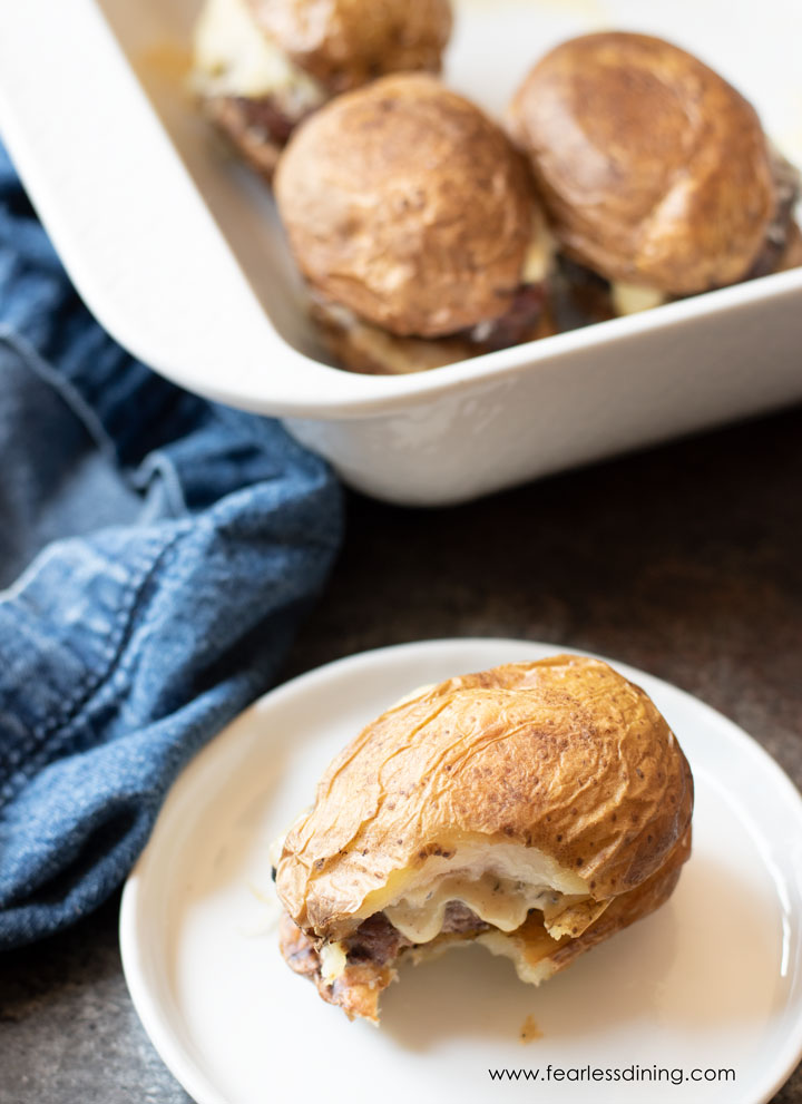 A lamb slider on a plate next to the baking dish of sliders.