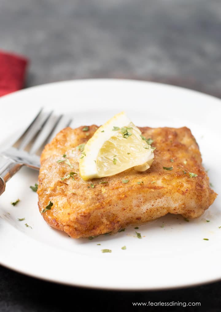 a piece of air fried cod on a plate. The cod is garnished with lemon