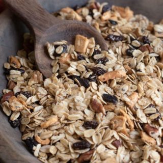 apple granola in a large wooden bowl with a wooden scoop