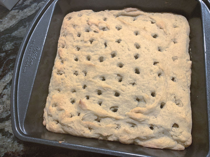 A cake with holes poked through the top for a poke cake.