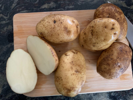 Washed potatoes on a cutting board.
