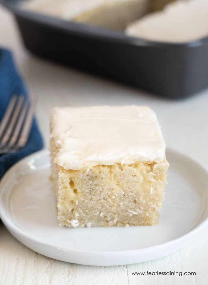 A frosted slice of gluten free poke cake on a plate.