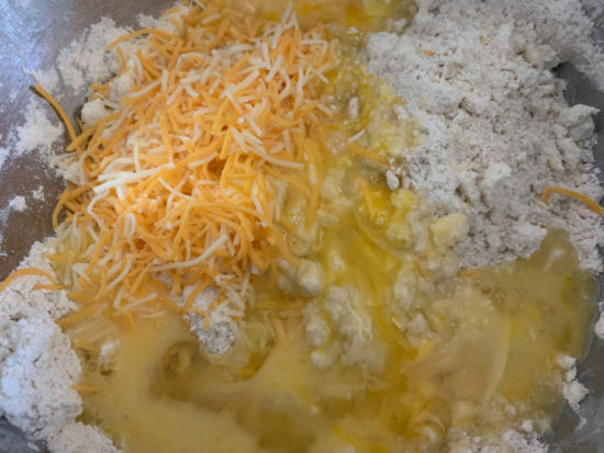 The pie crust ingredients with the shredded cheese and egg about to be mixed together.