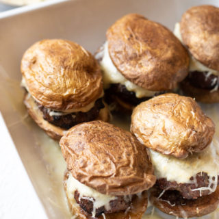 A white ceramic baking dish filled with lamb sliders.