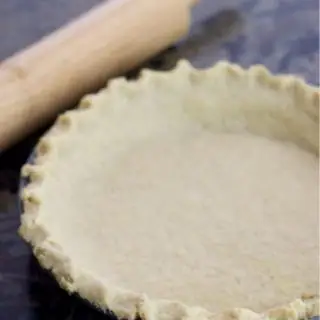 a baked flaky gluten free pie crust next to a rolling pin