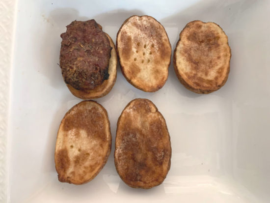 adding lamb burgers on the roasted potatoes