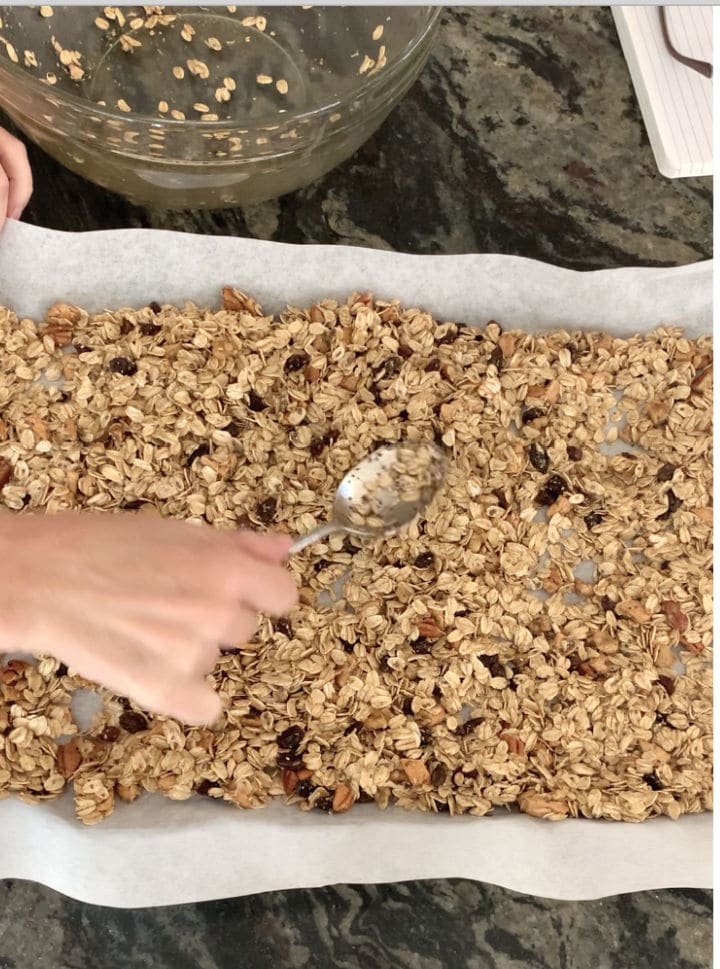 Spreading the granola on the cookie sheet before baking.