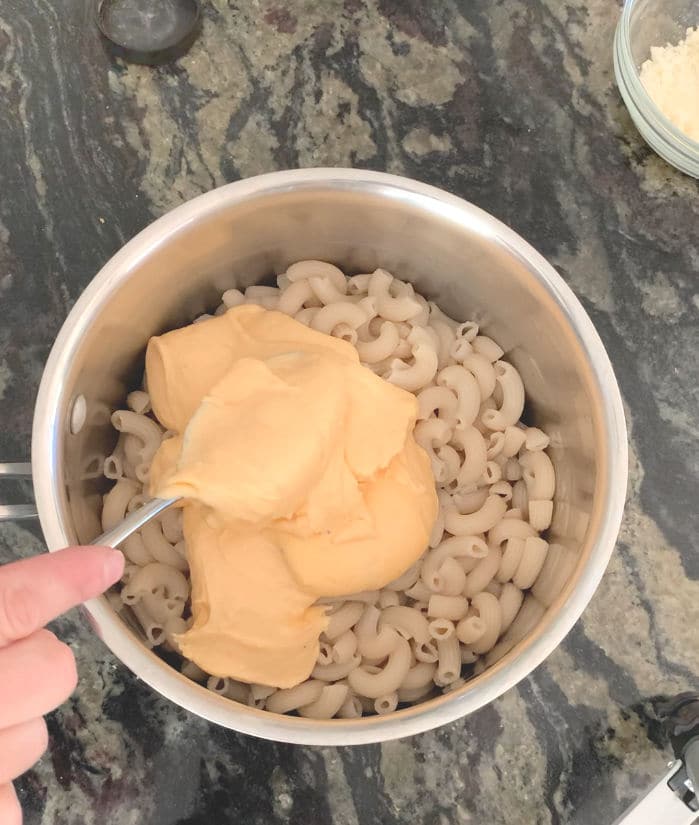 mixing the cheese sauce into the pasta.