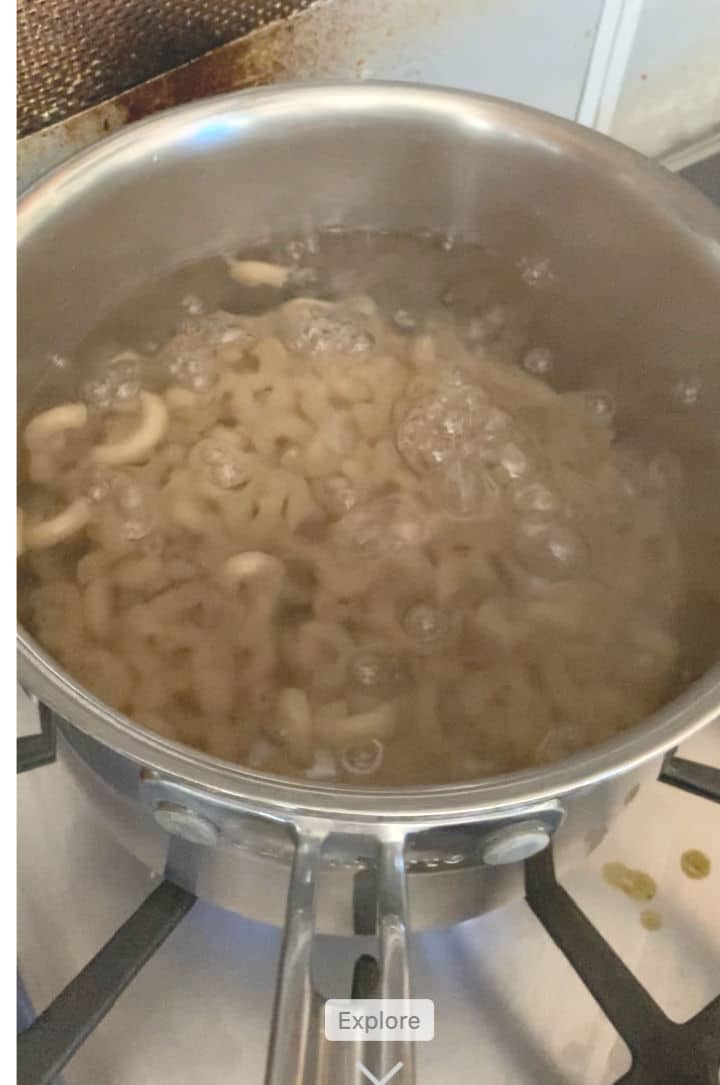 A pot of cooking macaroni on the stove.