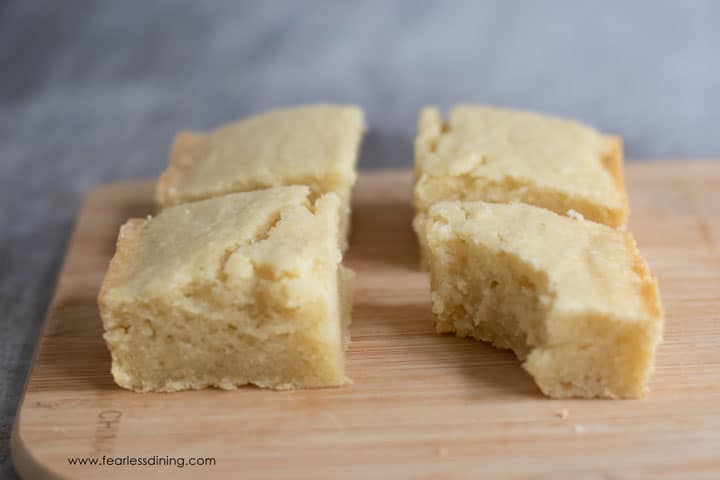 Four pieces of butter mochi on a cutting board.