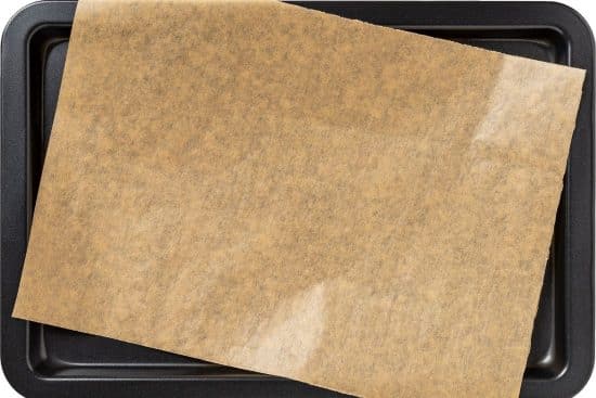 A cookie sheet with a piece of parchment paper on it.